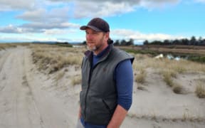 Ben Banks stands on the tracks among the dunes at the side of Thornton Lagoon
