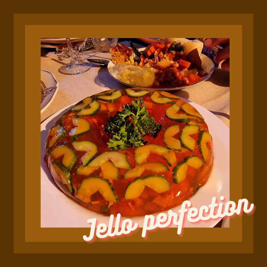 A photo of one of the dinner party dishes: a mound of vegetables encased in jelly and garnished with parsley. The image is framed with a brown 70s style border and the caption ''Jelly Perfection''