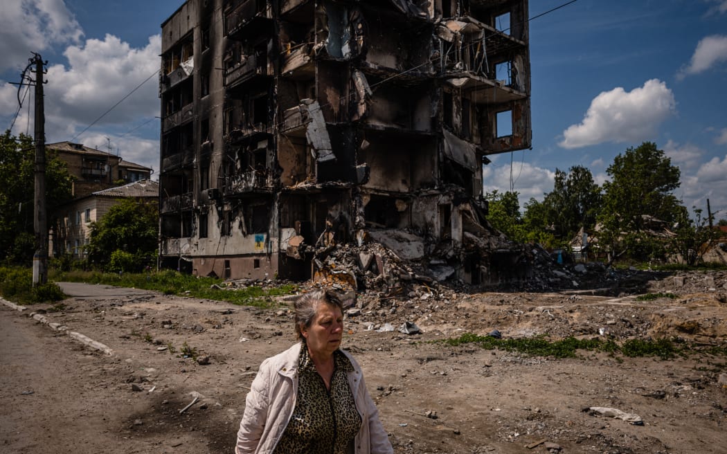 A woman walks past a destroyed apartment building in the town of Borodyanka on 1 June, 2022, amid the Russian invasion of Ukraine.