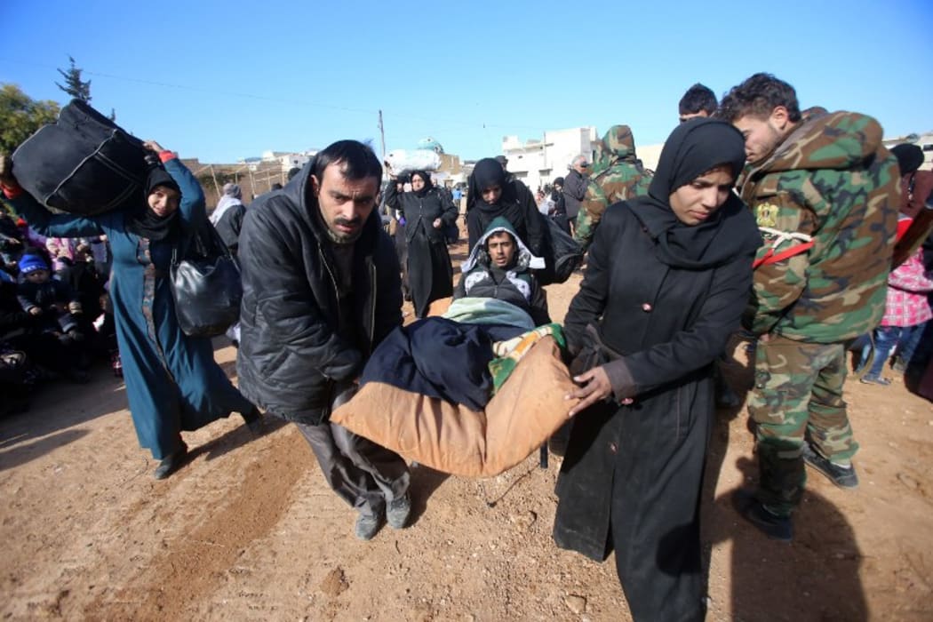 Syrian residents fleeing the violence gather at a checkpoint, manned by pro-government forces, in the village of Aziza on the southwestern outskirts of the northern Syrian city of Aleppo on December 8, 2016.