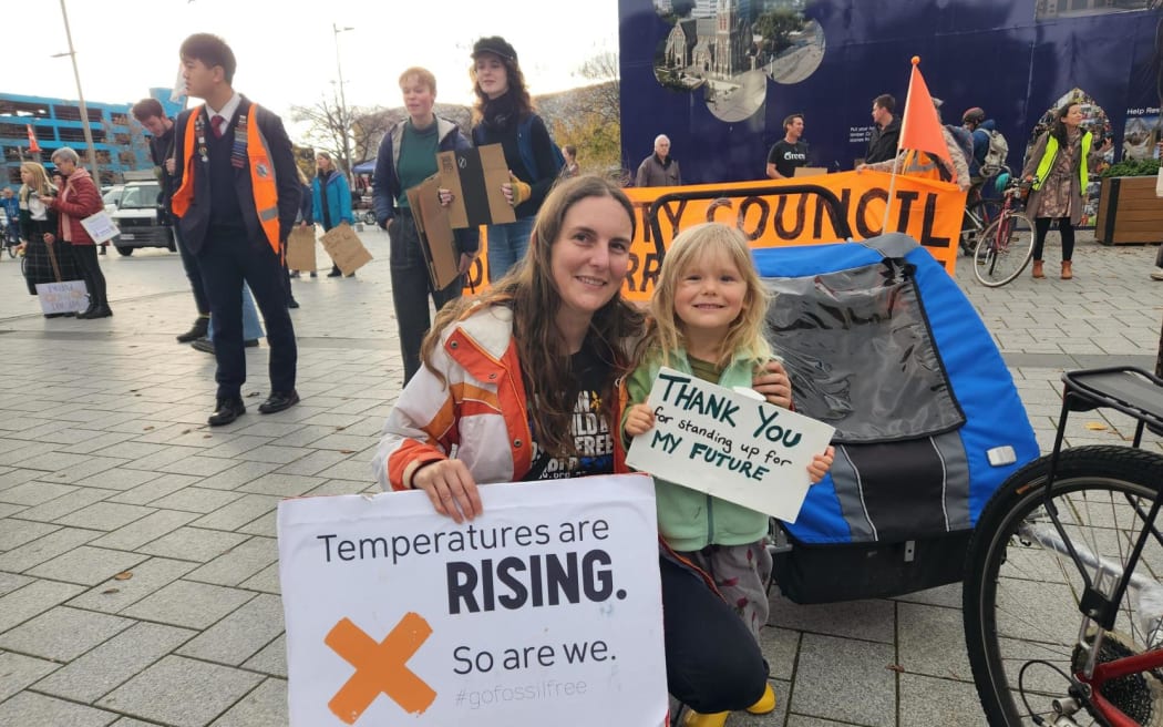 A mother and child hold placards at a climate strike on 26/5/2023