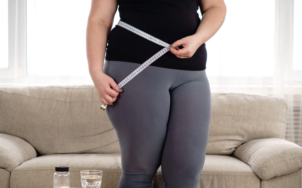 obese woman with pills and measure tape