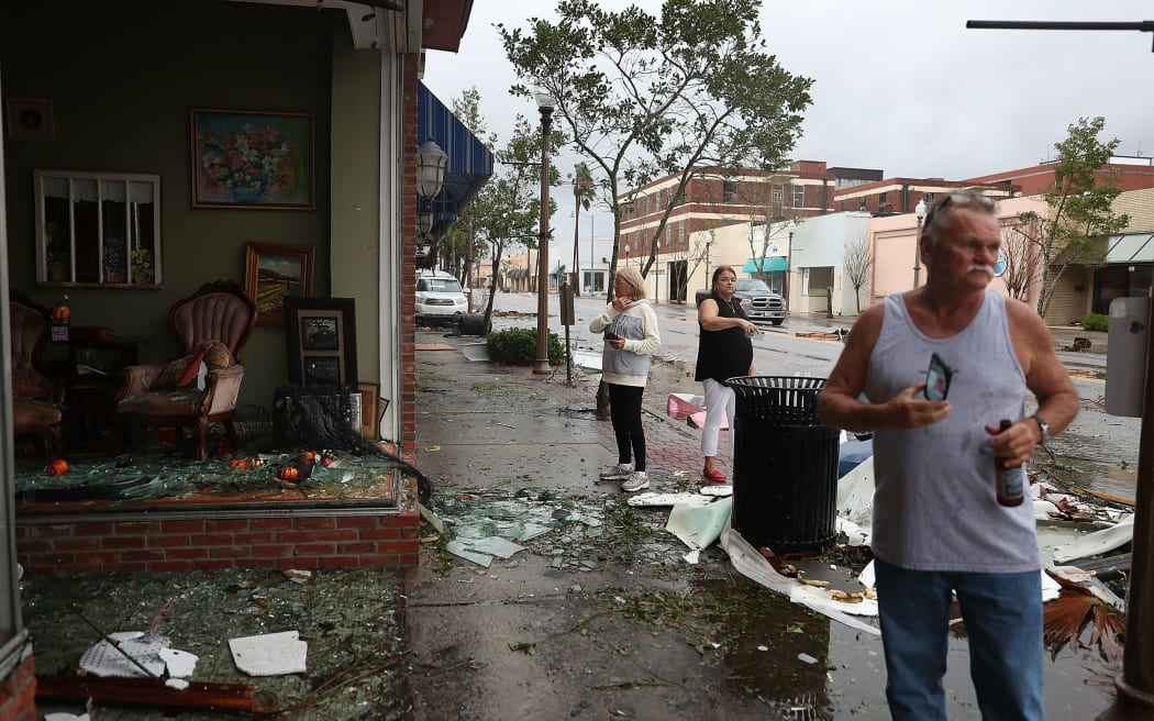 People walk past damaged stores after hurricane Michael passed through the downtown area of Panama City in Florida.