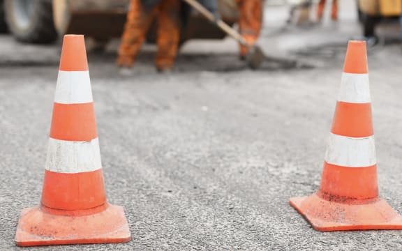 Road cones with road workers in background.