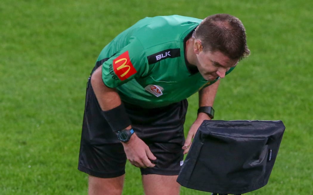 Referee Adam Kersey inspects video monitor before sending off Wellington Phoenix's Ryan Lowry.