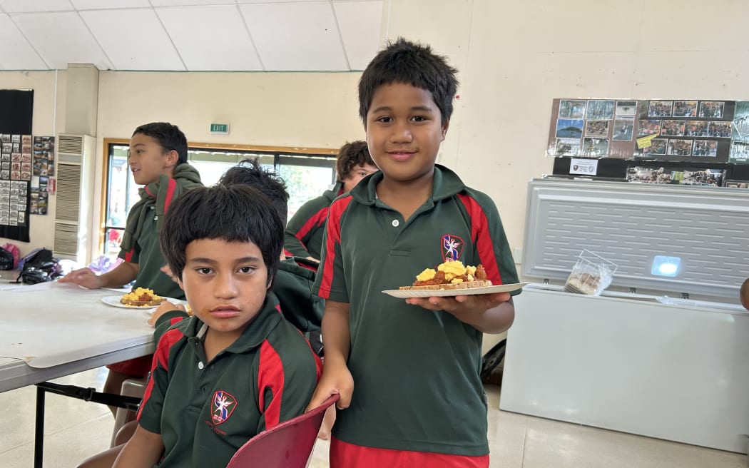 Students at Melville Primary are enjoying breakfast. A children is holding a plate of toast with sausages, and scrambled eggs.