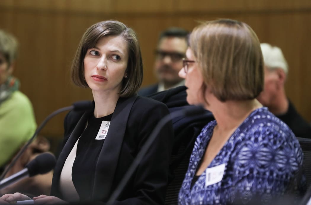 Lizzie Armstrong listens to her colleague Sally Stewart briefing a Select Committee for the Ministry of Health