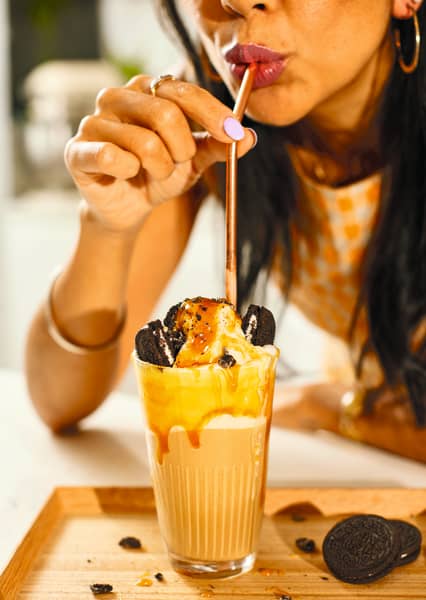 An image from Celeste Wong's book, Coffee Creations: 90 delicious recipes for the perfect cup. Celeste Wong sips on a caramel frappe.