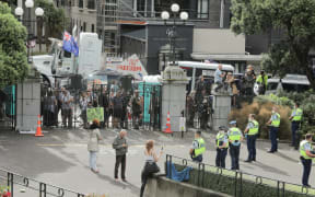 People watch on at the gates of Parliament as police make multiple arrests in an effort to remove protesters occupying the precinct for a third day.