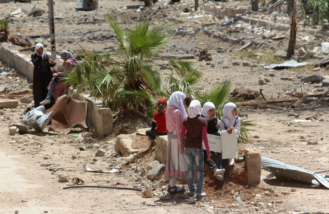 Syrian girls sit holding placards in the town of Daraya, southwest of central Damascus.