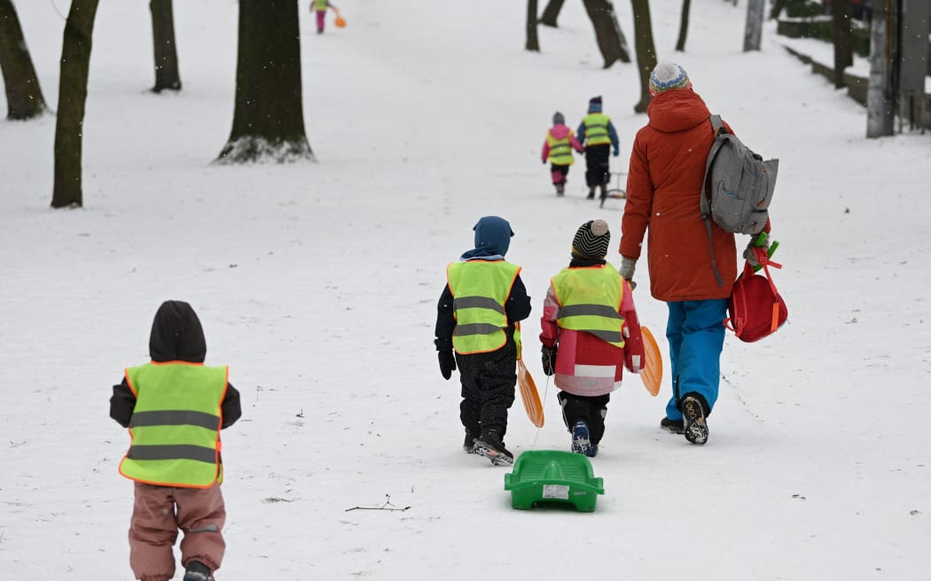 Young children pull a sledge as they walk up a slope through snow in the western Ukrainian city of Lviv on February 7, 2023, amid the Russian invasion of Ukraine. (Photo by YURIY DYACHYSHYN / AFP)