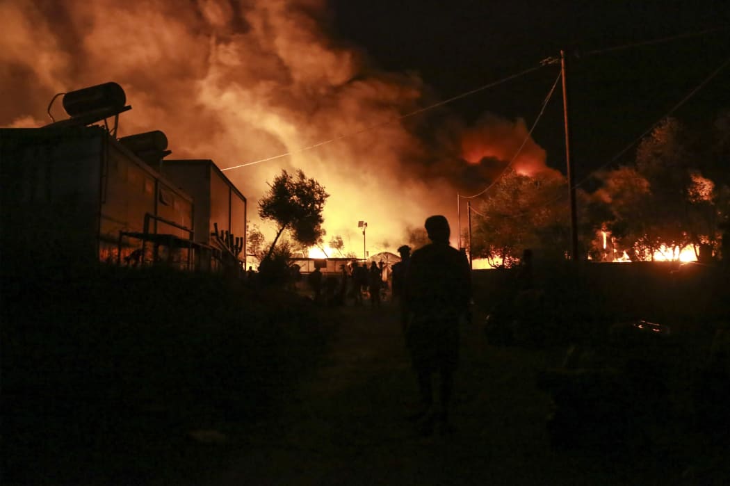 Migrants leave as a fire burns in the Moria camp on the island of Lesbos on September 9, 2020.