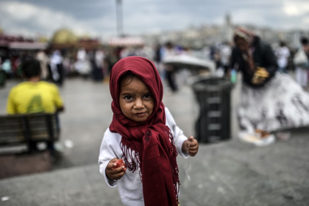 A Syrian child with food which her mother, right, collects from rubbish in Istanbul, Turkey.