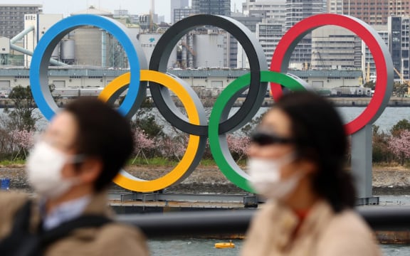 People wearing a mask walk near the Olympics' mark in Odaiba, Tokyo, amid the outbreak of a new coronavirus in Japan.
