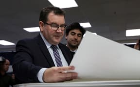 Grant Robertson looking over the first print of his first budget.