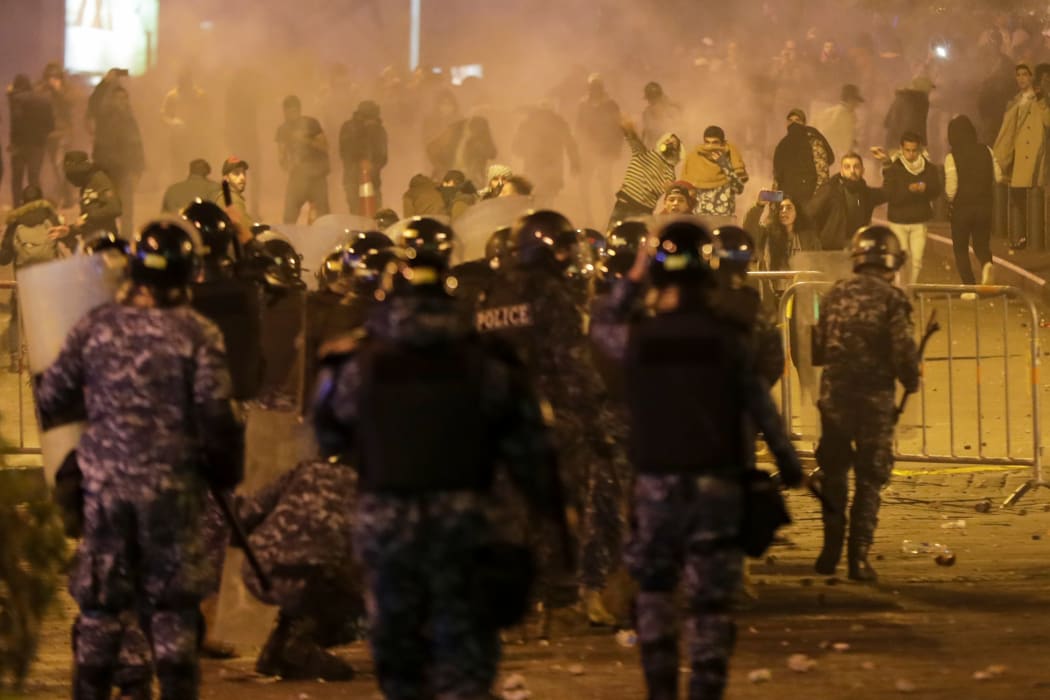 Lebanese riot police clash with anti-government demonstrators (background) in Beirut.