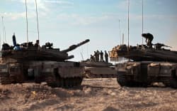 Israeli troops and tanks gather in a field near the kibbutz Beeri in southern Israel on October 14, 2023, close to the spot where 270 revellers were gunned down or burnt in their cars by Hamas gunmen at the Supernova music festival in the Negev desert on October 7. Hamas launched a large-scale attack on Israel on October 7 which killed at least 1300 people, sparking a retaliatory bombing campaign that has killed more than 1900 in the Gaza Strip ahead of a potential Israeli ground invasion of the territory. (Photo by Thomas COEX / AFP)