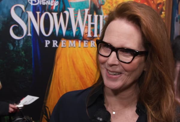 Erin Cressida Wilson, a woman with dark-rimmed glasses and long brown hair, speaks to a report on a red carpet.