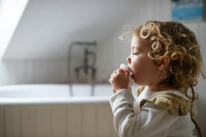 A little kid using a tissue.