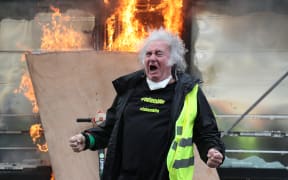 A Yellow Vest protester gestures in front of a newsstand set alight during clashes with riot police forces on the Champs-Elysees in Paris on March 16.
