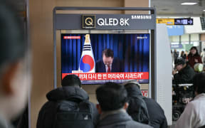 People watch a live television broadcast of South Korea's President Yoon Suk Yeol bowing after the end of his address, at a train station in Seoul on December 7, 2024. - South Korean President Yoon Suk Yeol apologised on December 7 for the confusion caused by his declaration of martial law and said he will let his party decide on his future position. (Photo by ANTHONY WALLACE / AFP)