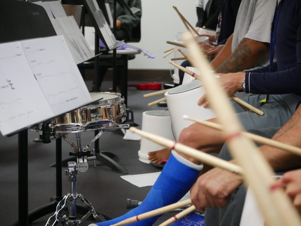 Participants of a music course at Chch men's prison drum on buckets with members of the CSO
