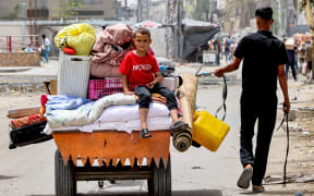 A boy looks on as he sits atop cushions and mattresses loaded in the back of an animal-drawn cart led by a man as they evacuate from Sheikh Zayed in the northern Gaza Strip on May 11, 2024 amid the ongoing conflict in the Palestinian territory between Israel and Hamas. (Photo by AFP)