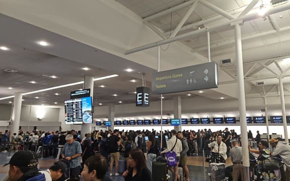 Passengers queue at Auckland International Airport after their flight to Santiago, Chile was cancelled. The plane they were meant to fly on experienced a "technical problem" that saw 13 people hospitalised, one with serious injuries.