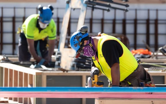 Masked construction workers are pictured at a building site on the first day of the easing of restrictions in Wellington on April 28, 2020, following the COVID-19 coronavirus outbreak. -