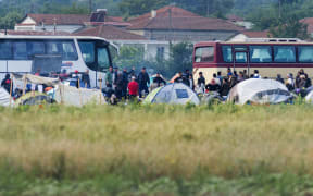 Greek police officers move refugees from one camp to another.