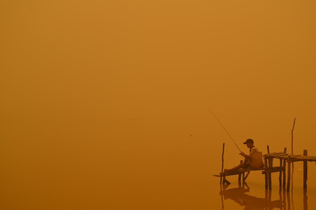 A resident fishes by the river in Palangkaraya city, Indonesia, one of worst-hit by haze in central Kalimantan province.