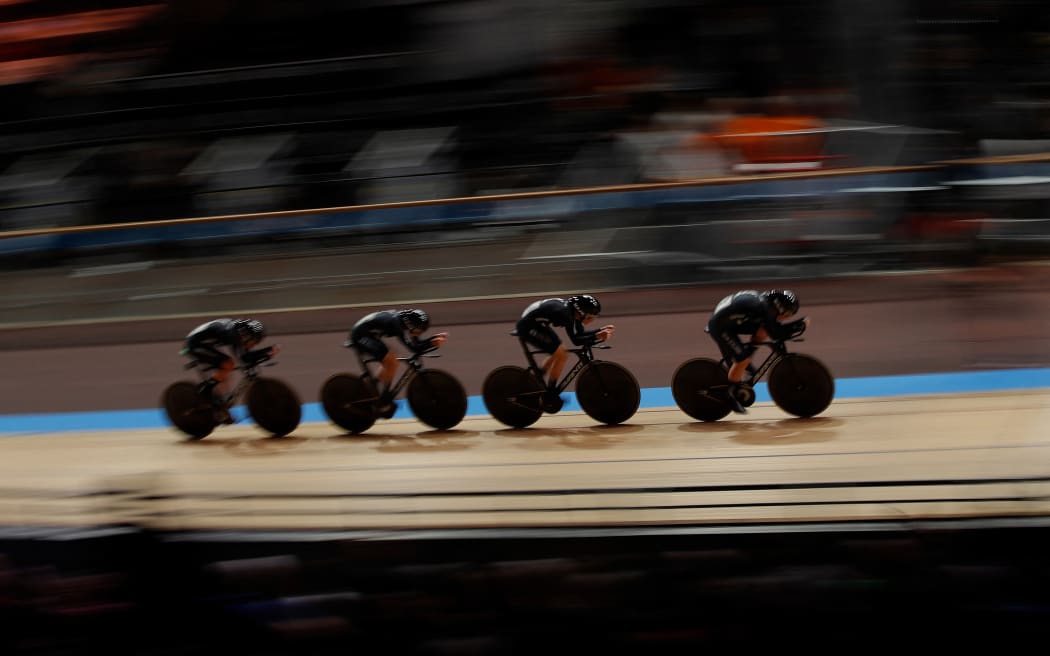 A New Zealand track cycling team of 4 riders cycle in the velodrome.