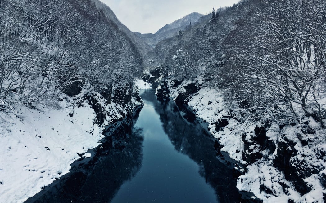 The Tone River with snowy banks in winter. Minakami, Japan