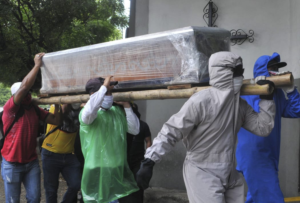 Relatives of a person who died from Covid-19 carry the wrapped coffin inside a cemetery in Ecuador yesterday.
