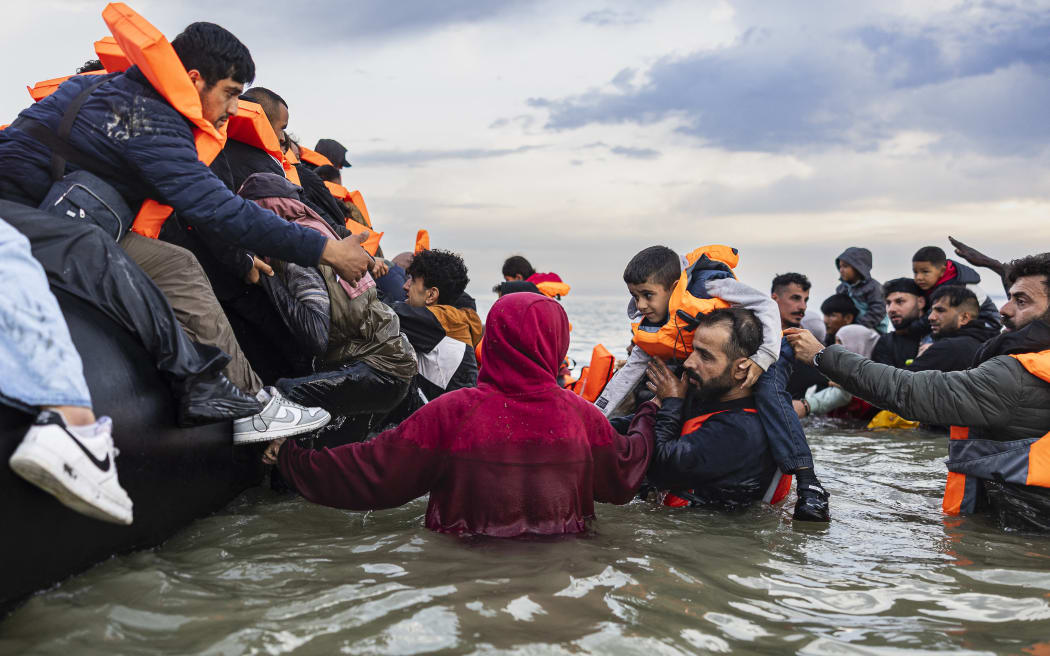 Migrants try to board a smuggler's boat in an attempt to cross the English Channel off the beach of Gravelines, northern France on August 12, 2025.