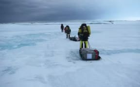 Scientists traversing smooth landfast ice to take core samples near Casey Station, Antarctica.