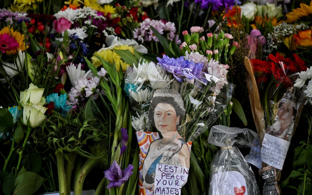 Flowers and pictures of the late Queen Elizabeth II are placed outside of the Palace of Holyroodhouse in Edinburgh on September 11, 2022. - Queen Elizabeth II's coffin will travel by road through Scottish towns and villages on Sunday as it begins its final journey from her beloved Scottish retreat of Balmoral. The Queen, who died on September 8, will be taken to the Palace of Holyroodhouse before lying at rest in St Giles' Cathedral, before travelling onwards to London for her funeral.. (Photo by Louisa Gouliamaki / AFP)