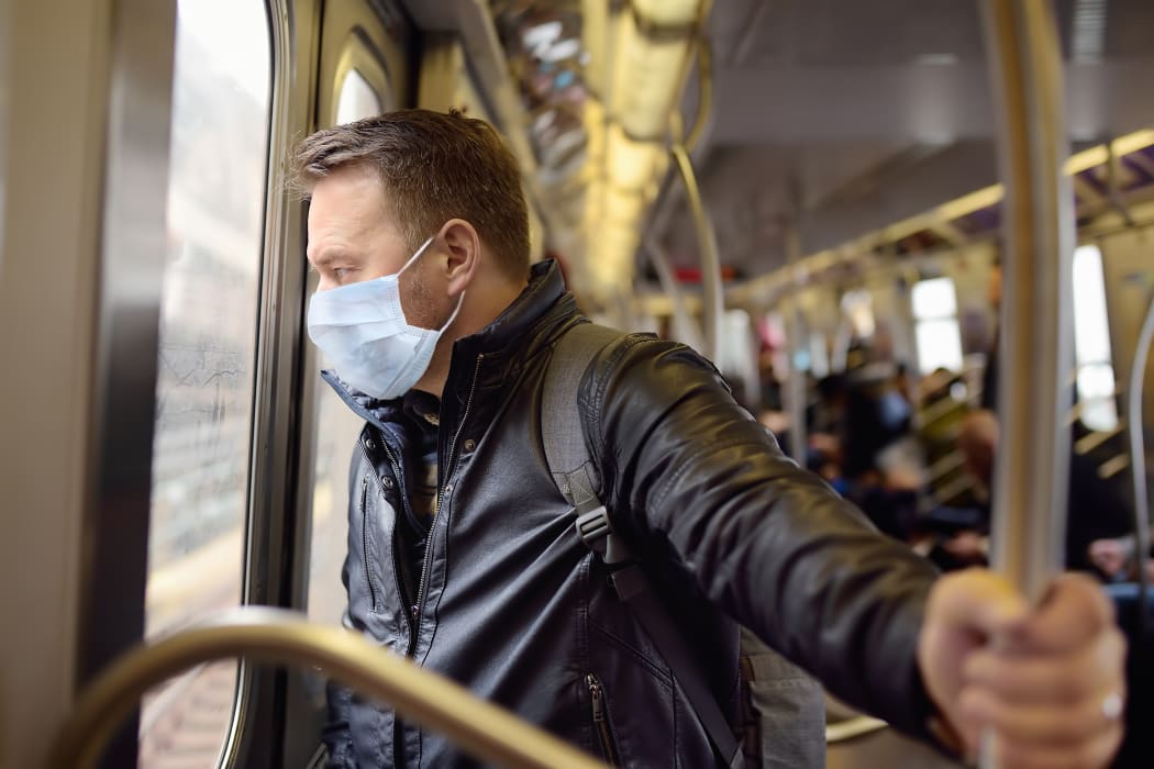 A man wearing a disposable medical face mask in car of a subway in New York during coronavirus outbreak.