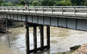 Crews worked to restore a cable which was torn from a bridge near Tologa Bay by the swollen Hikuwai River after Cyclone Hale.