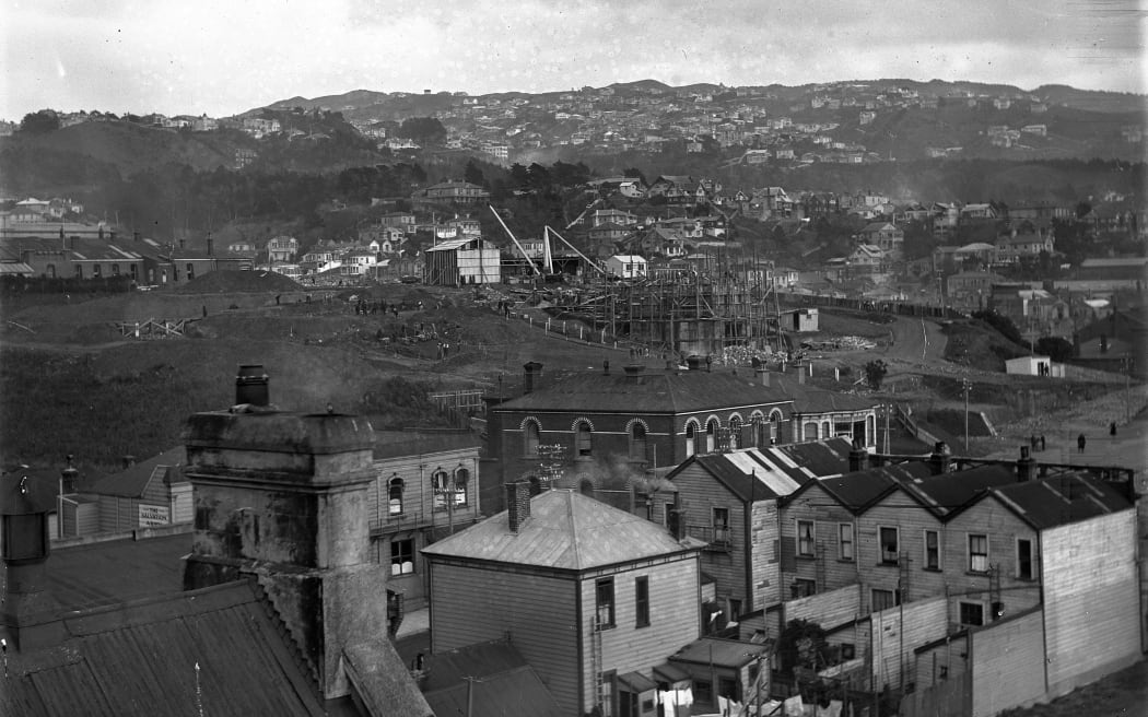 Looking west over Mt Cook in 1931. Shows the police barracks in the middle ground (brick building, arched windows), the back of houses on Tory Street (right) and the carillon under construction. 
 Mt Cook, Wellington, Carillon under construction.