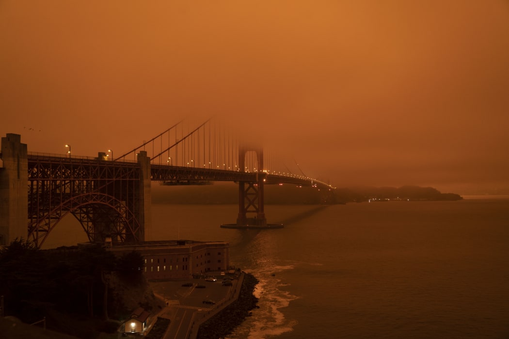 Cars drive along the San Francisco Bay Bridge under an orange smoke filled sky at midday in San Francisco, California on 9 September, 2020.