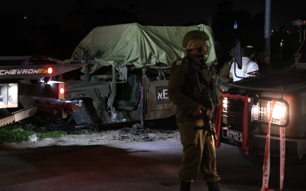 Israeli soldiers surround a damaged military vehicle at the site of a ramming attack near the town of Beit Ummar, north of Hebron city in the occupied West Bank, on April 1, 2023. (Photo by AHMAD GHARABLI / AFP)