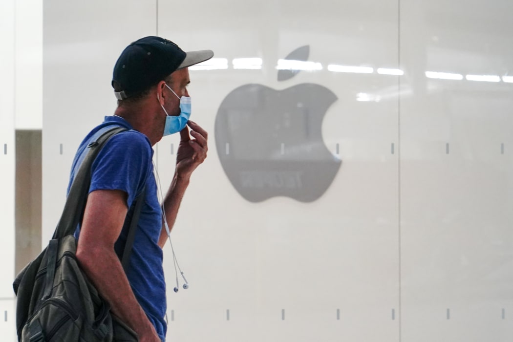 A man wearing a mask past an Apple store in New York City.