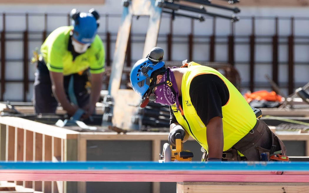 Masked construction workers are pictured at a building site on the first day of the easing of restrictions in Wellington on April 28, 2020, following the COVID-19 coronavirus outbreak. -