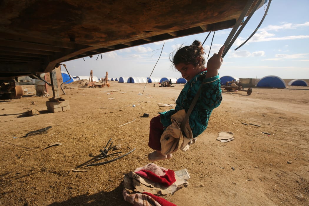 A displaced Iraqi girl plays on a swing at the Al-Agha camp where Iraqi families from the nearby villages of Tal Afar, southwest of Mosul, are taking shelter as Iraqi forces continue their military operation to recapture Mosul from Islamic State (IS) jihadists on February 16, 2017.