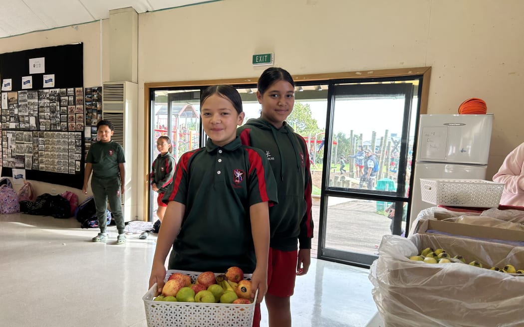 Picture of two primary school aged children, holding a fruit basket.