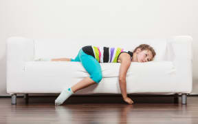 Tired exhausted lazy little girl lying on sofa at home. Sleepy kid resting relaxing on couch.