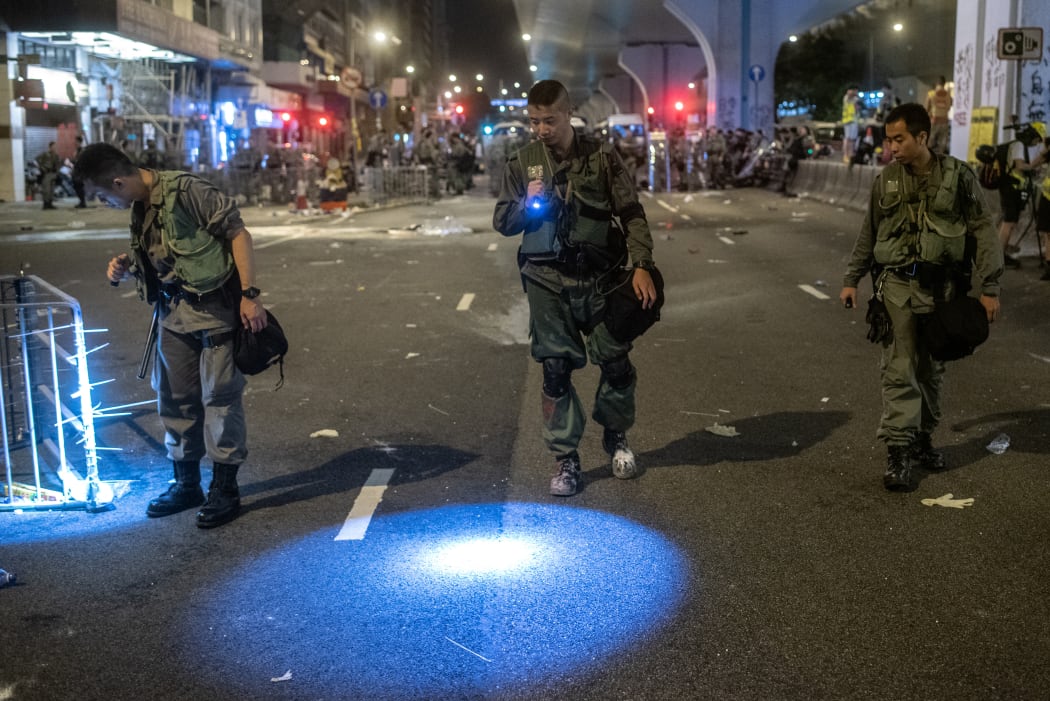 Police officers searching for evidence after clashes with protesters following a march against a controversial extradition bill in Hong Kong early.
