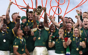 South Africa's flanker and captain Siya Kolisi (C) lifts the Webb Ellis Cup on the podium after South Africa won the France 2023 Rugby World Cup final between New Zealand and South Africa at the Stade de France on 28 October, 2023.