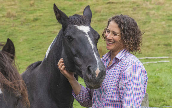 Storm Baynes-Ryan smiling and stroking a black horse